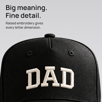 Close detail of raised ivory DAD embroidery on black cotton twill. Big meaning. Fine detail.