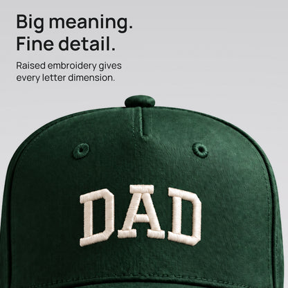 Close detail of raised ivory DAD embroidery on forest green cotton twill. Big meaning. Fine detail.