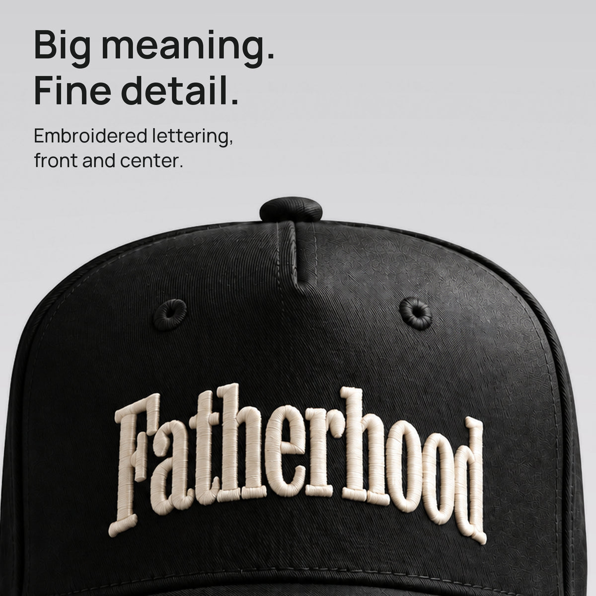 Close detail of ivory Fatherhood lettering embroidered on black cotton twill. Big meaning. Fine detail.