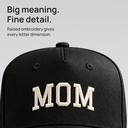 Close-up of ivory MOM embroidery on the black cap. Fine detail. Raised collegiate lettering on cotton twill.