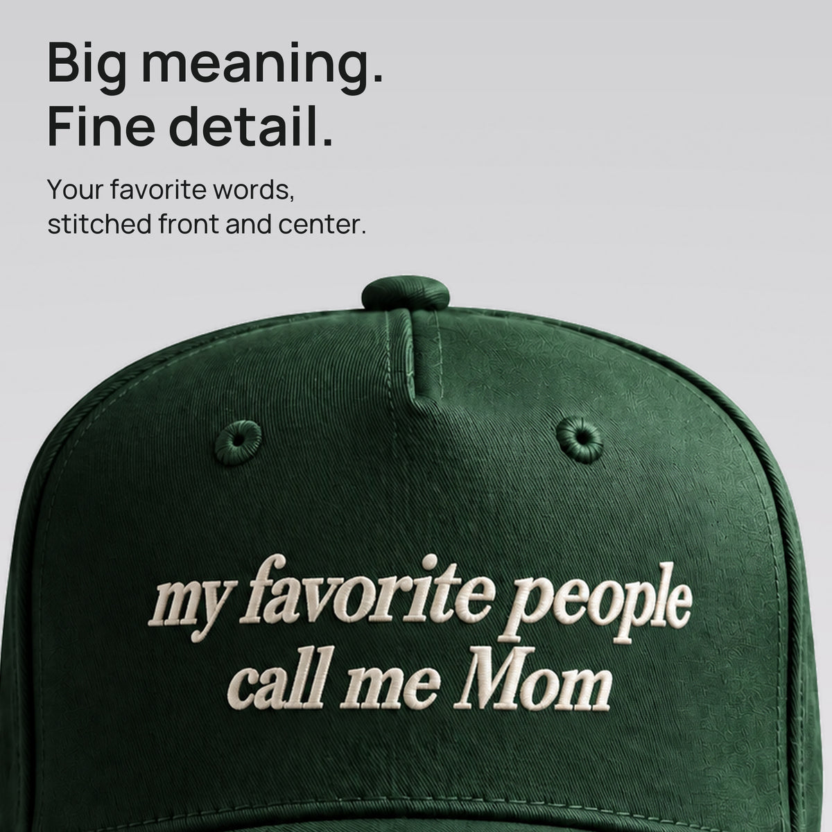 Close detail of ivory My Favorite People Call Me Mom embroidery on forest green cotton twill.