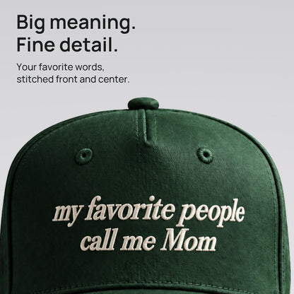 Close detail of ivory My Favorite People Call Me Mom embroidery on forest green cotton twill.