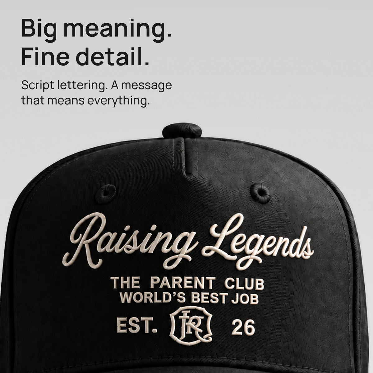 Close detail of ivory Raising Legends script embroidered on black cotton twill. Big meaning. Fine detail.