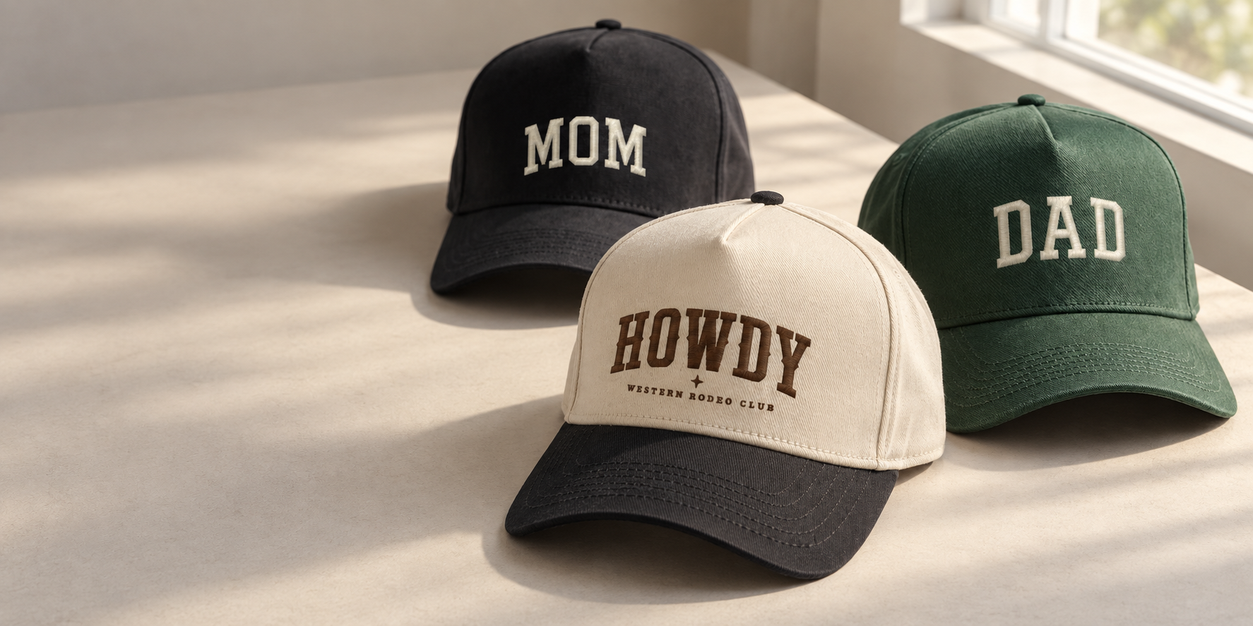 MOM, DAD, and HOWDY hats resting on an off-white table in natural window light